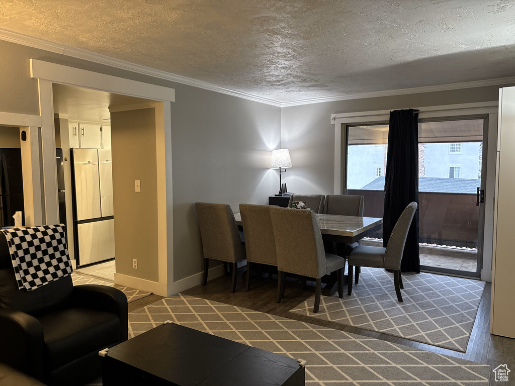 Dining area with crown molding, baseboards, a textured ceiling, and wood finished floors