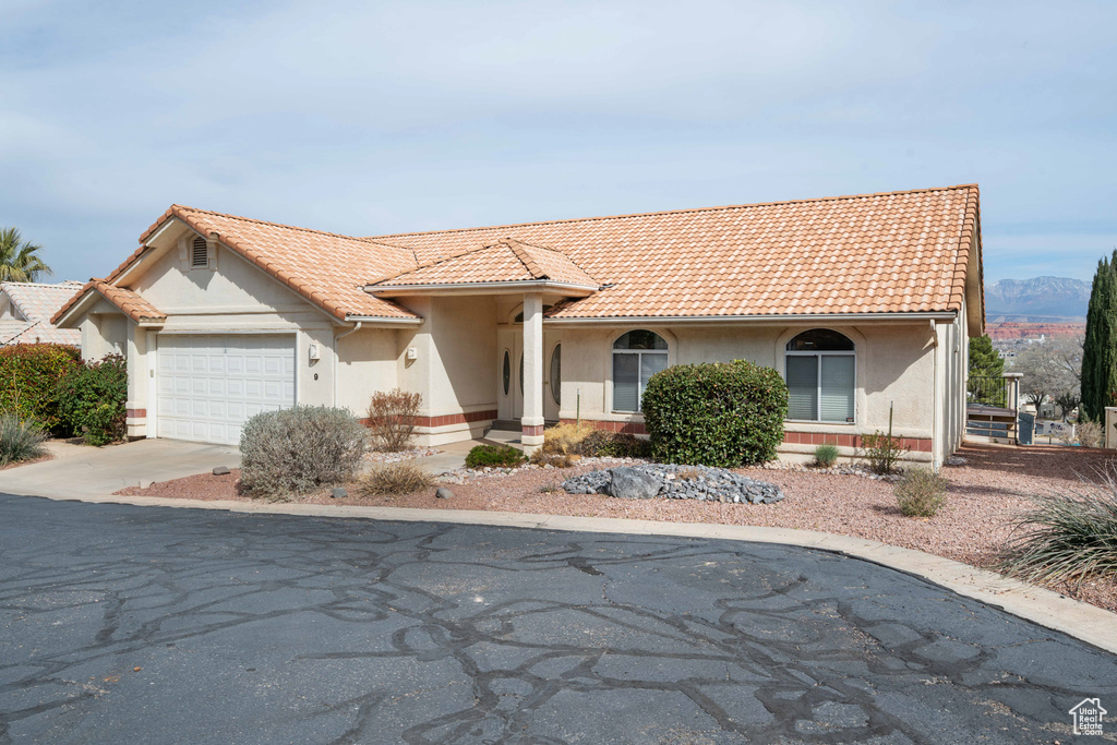 Mediterranean / spanish house with concrete driveway, a tiled roof, a garage, and stucco siding