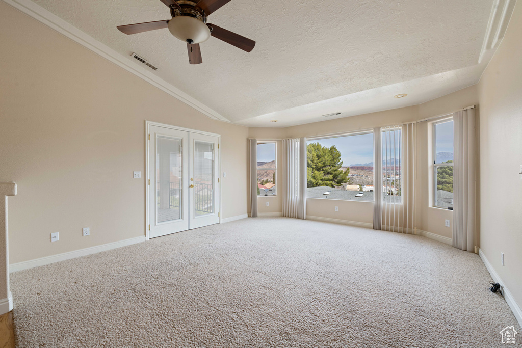 Carpeted empty room with vaulted ceiling, french doors, visible vents, and a textured ceiling