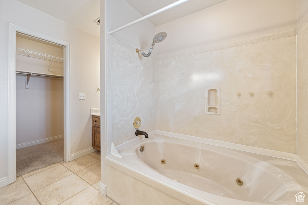 Bathroom with vanity, baseboards, a combined bath / shower with jetted tub, a walk in closet, and tile patterned floors