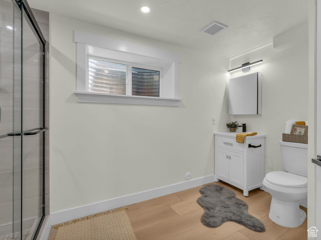 Full bath with vanity, toilet, a stall shower, wood finished floors, and recessed lighting