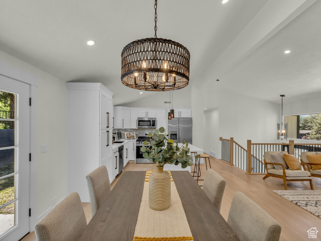 Dining room featuring a chandelier, recessed lighting, light wood-style flooring, and vaulted ceiling