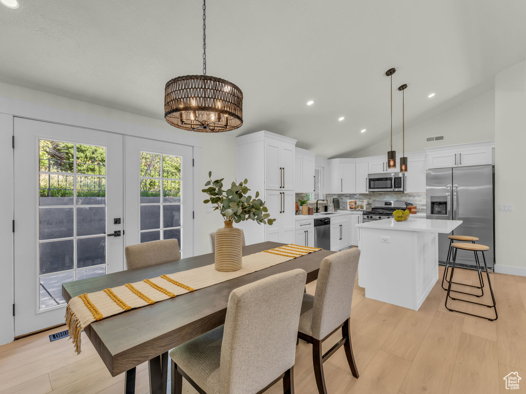 Dining space featuring a chandelier, lofted ceiling, recessed lighting, and light wood-style flooring