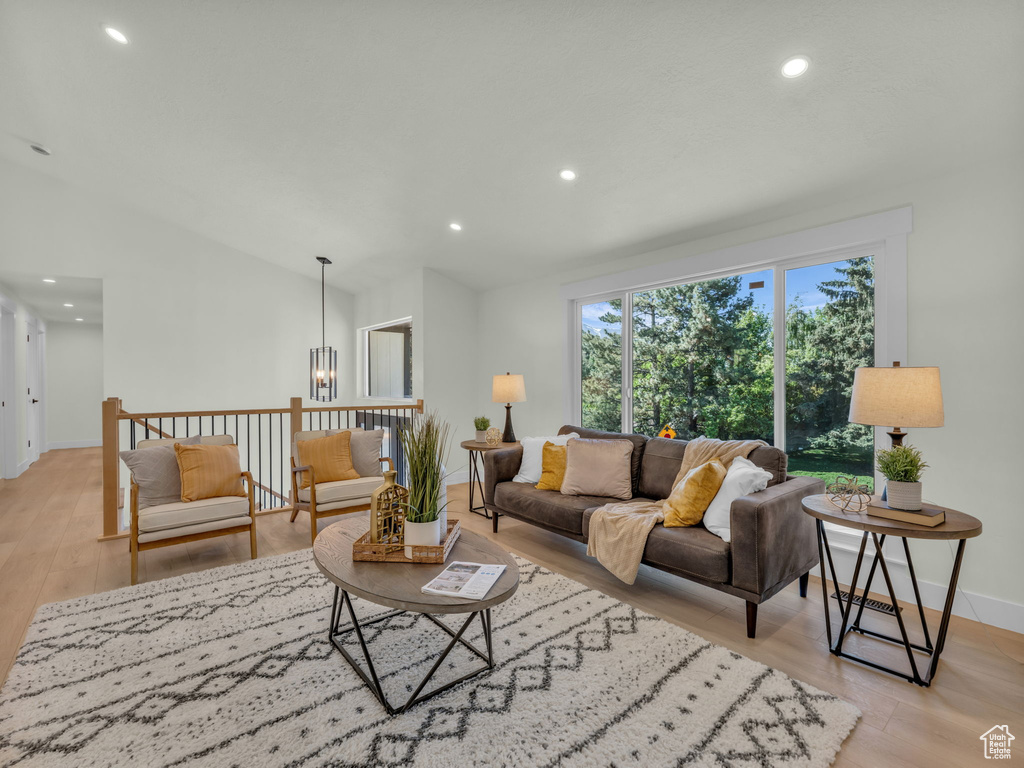 Living area featuring light wood finished floors, baseboards, recessed lighting, lofted ceiling, and a chandelier