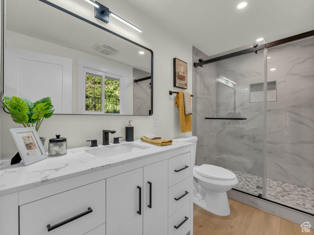 Bathroom featuring vanity, a marble finish shower, toilet, and recessed lighting