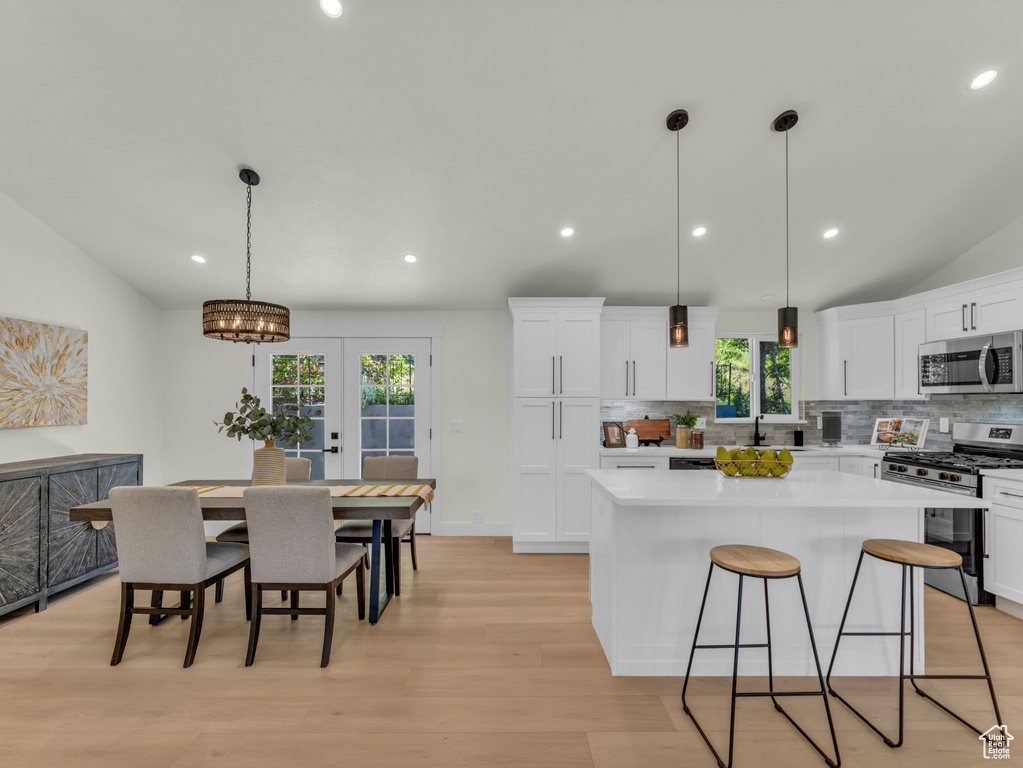 Kitchen with stainless steel appliances, a center island, decorative backsplash, recessed lighting, and white cabinetry