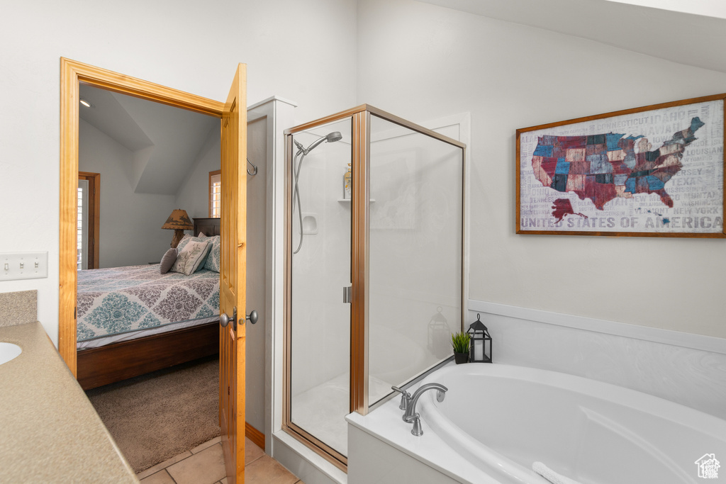 Bathroom featuring tile patterned floors, a stall shower, ensuite bath, lofted ceiling, and a bath