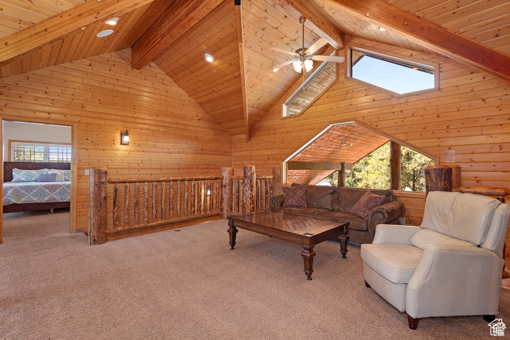 Living area featuring beamed ceiling, wooden walls, carpet floors, and ceiling fan