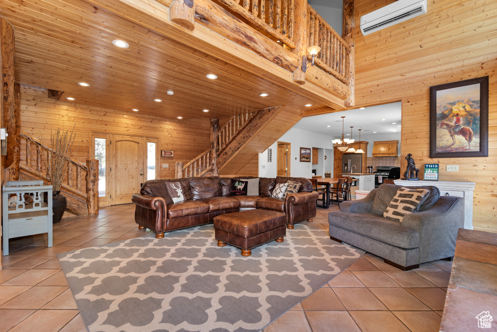 Living area featuring light tile patterned floors, an inviting chandelier, wood walls, and stairs