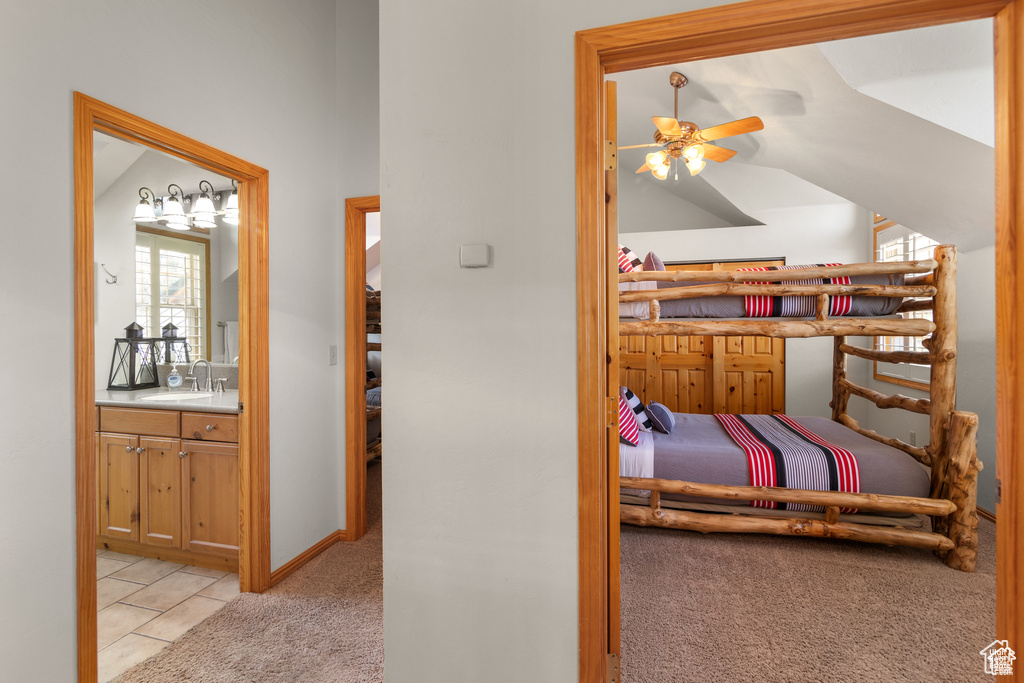 Bedroom with light carpet, vaulted ceiling, ensuite bathroom, and a sink