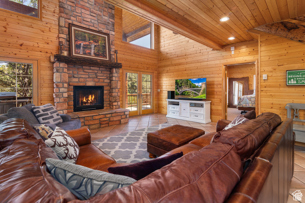 Tiled living room featuring recessed lighting, a stone fireplace, wooden ceiling, wood walls, and a towering ceiling