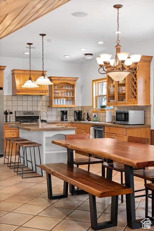 Kitchen with an inviting chandelier, open shelves, stainless steel appliances, decorative backsplash, and hanging light fixtures