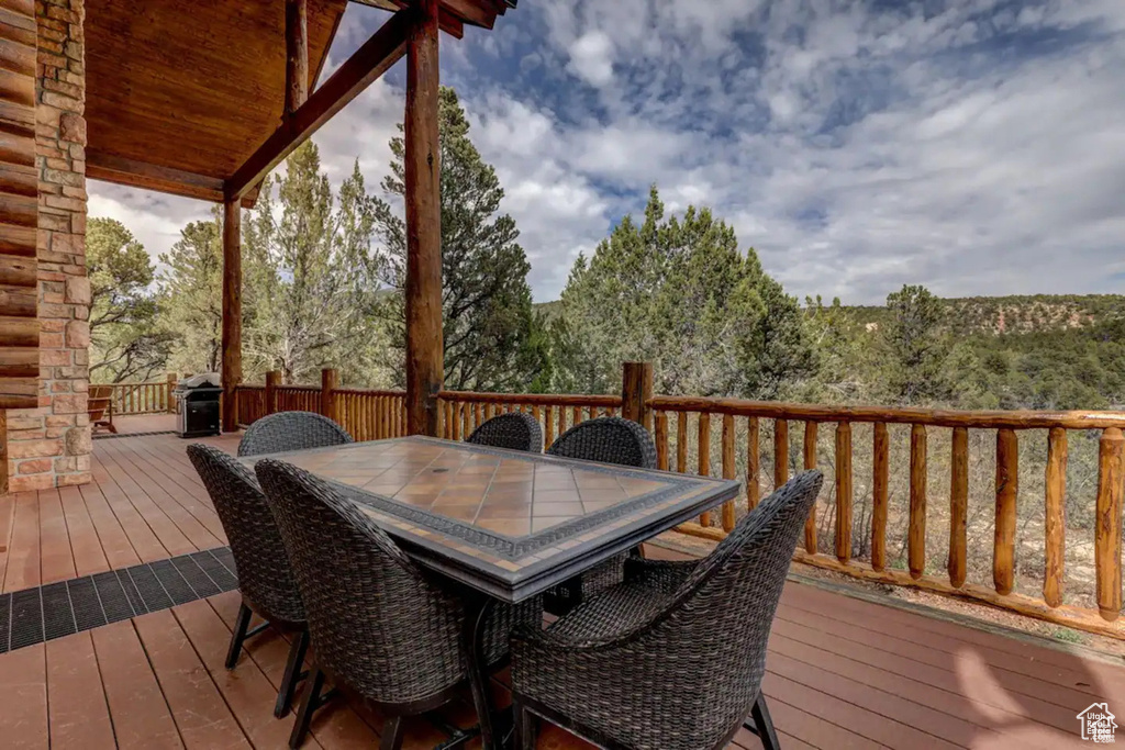 Wooden terrace featuring outdoor dining space and grilling area