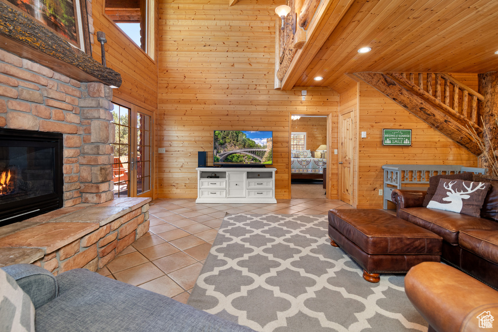 Living area with wooden walls, recessed lighting, a stone fireplace, tile patterned floors, and wooden ceiling