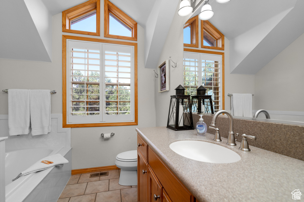 Bathroom with vanity, a bath, visible vents, vaulted ceiling, and toilet