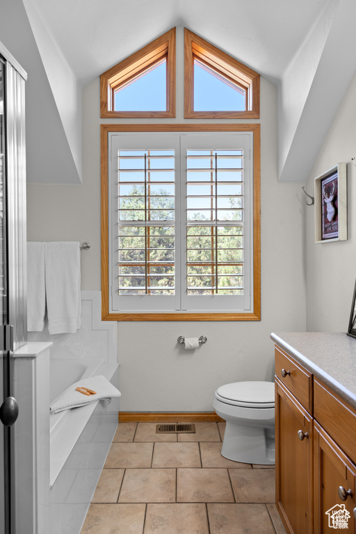 Full bathroom with visible vents, toilet, a garden tub, lofted ceiling, and vanity