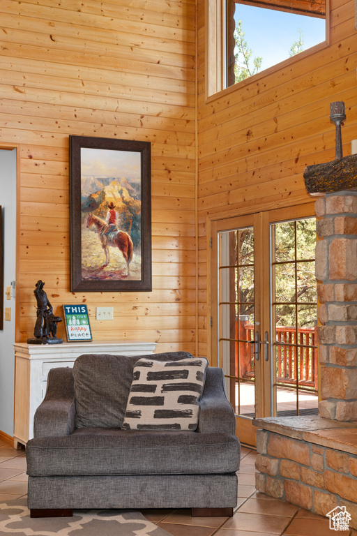 Living area featuring french doors, a high ceiling, wooden walls, and tile patterned flooring