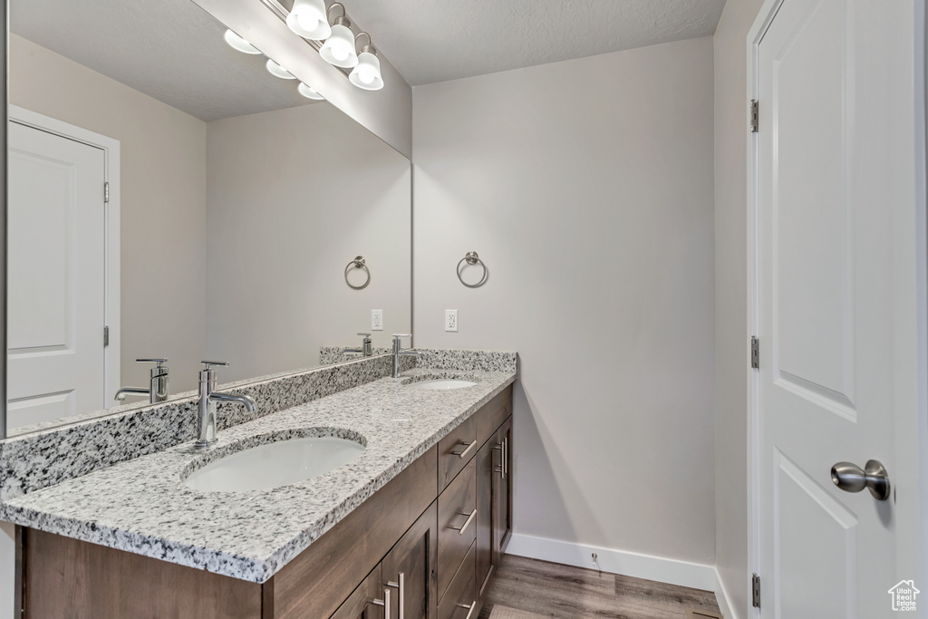 Bathroom with double vanity, wood finished floors, baseboards, and a sink
