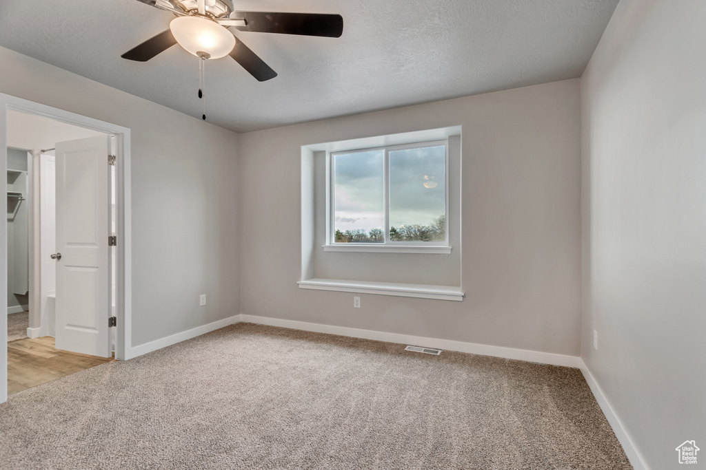 Unfurnished room with baseboards, light colored carpet, visible vents, and ceiling fan