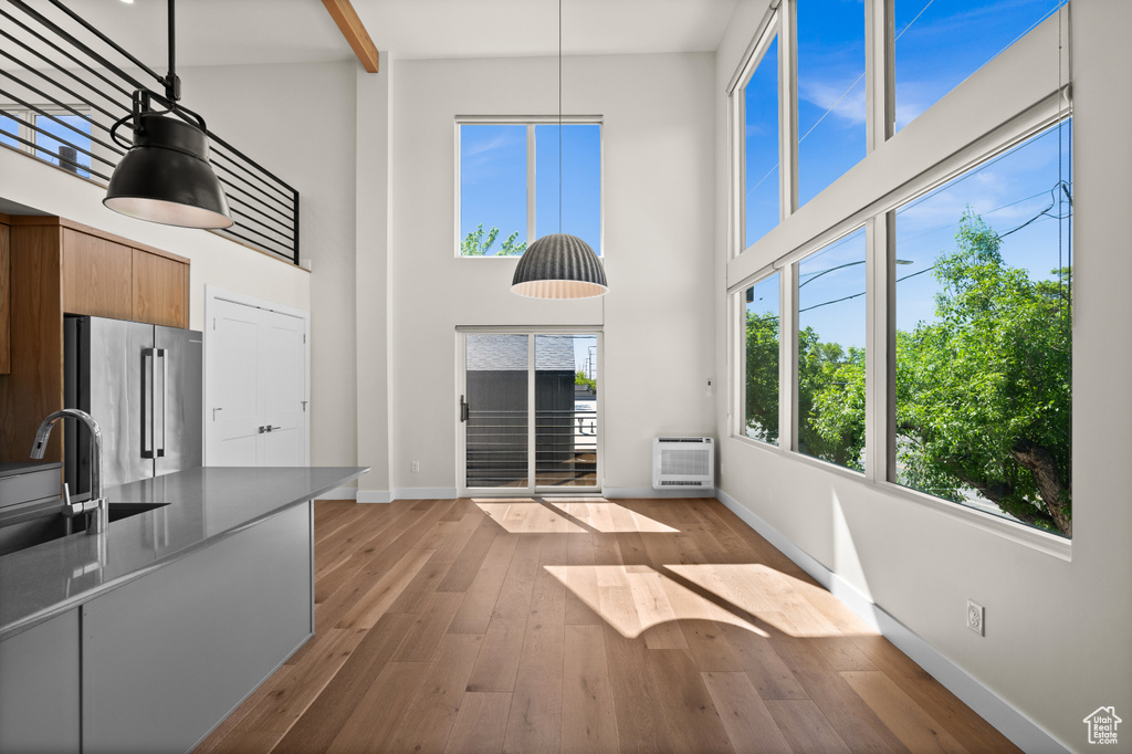 Unfurnished living room with baseboards, a sink, a high ceiling, wood-type flooring, and a wall mounted AC