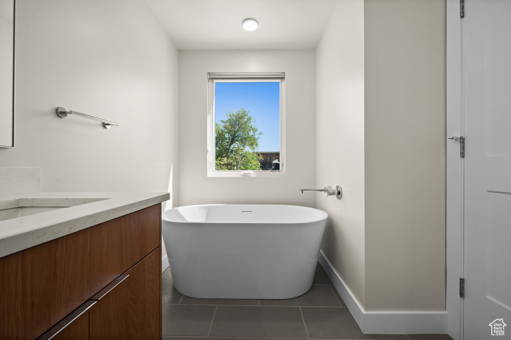 Bathroom with a freestanding bath, vanity, tile patterned flooring, and baseboards