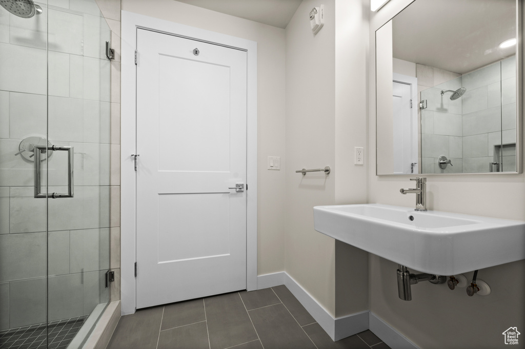 Bathroom with a stall shower, baseboards, and tile patterned floors