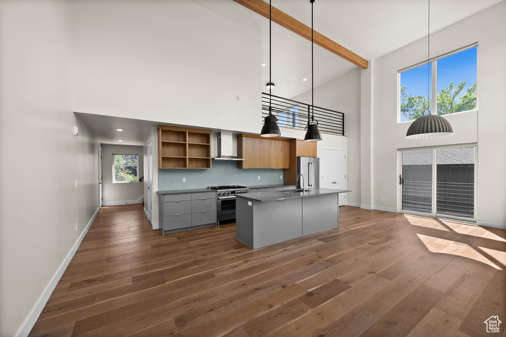 Kitchen featuring high vaulted ceiling, high quality appliances, wall chimney exhaust hood, open shelves, and dark wood-type flooring