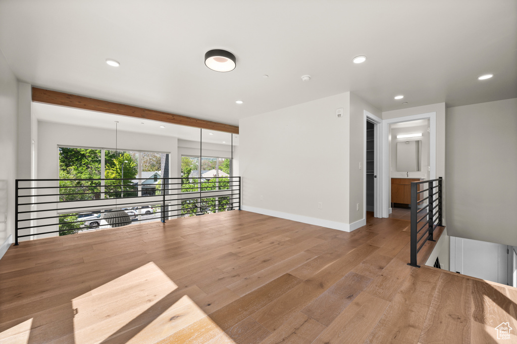 Empty room featuring recessed lighting, wood finished floors, baseboards, and beam ceiling