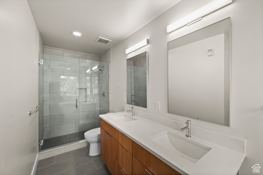 Full bath with toilet, a shower stall, tile patterned flooring, and double vanity