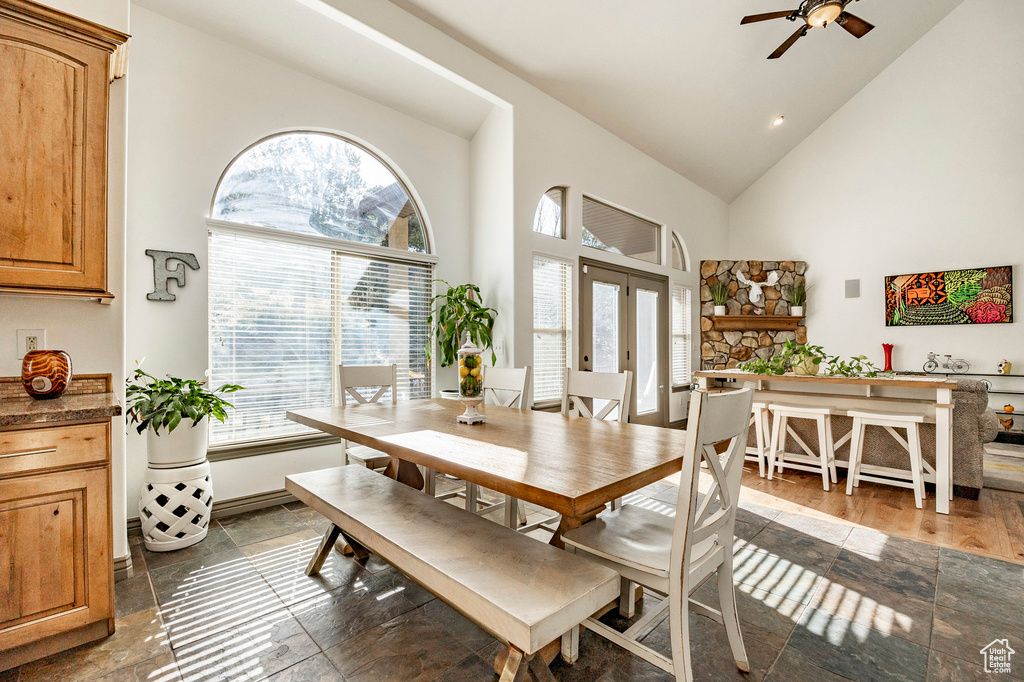 Dining area with high vaulted ceiling, healthy amount of natural light, a ceiling fan, and french doors