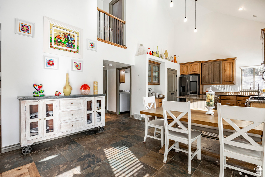Dining space with a towering ceiling, stone tile flooring, baseboards, and washer / clothes dryer