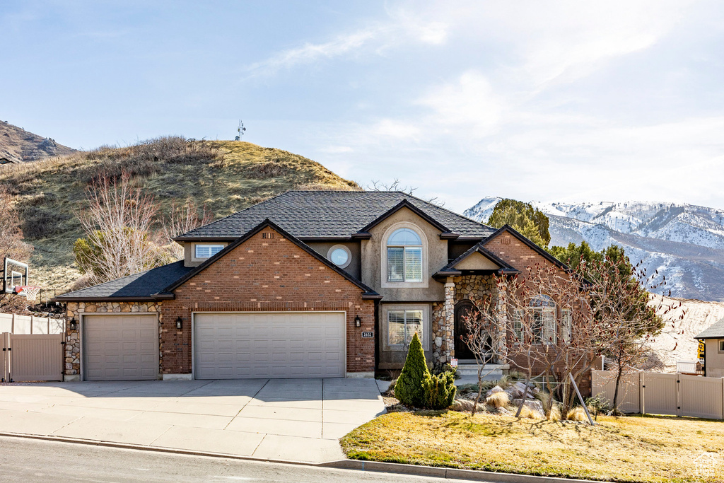 Traditional home with a gate, a mountain view, a garage, and fence