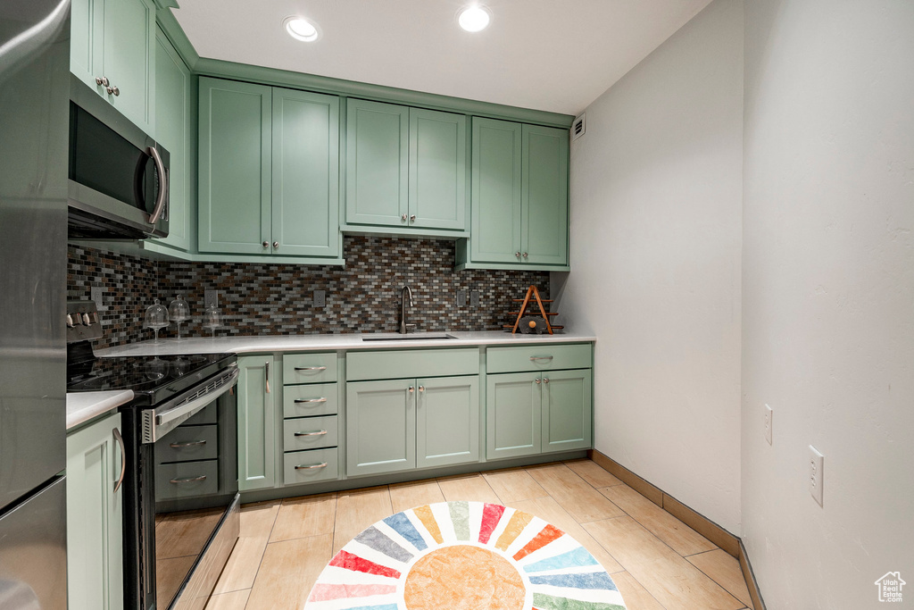 Kitchen featuring green cabinetry, stainless steel appliances, a sink, and recessed lighting