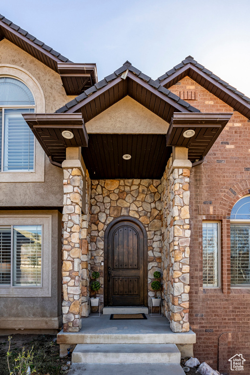 View of exterior entry with stucco siding, stone siding, and brick siding
