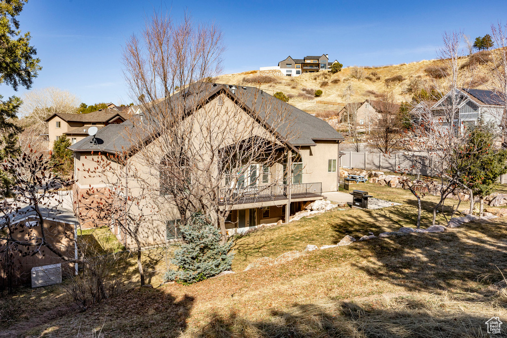 Rear view of property featuring a wooden deck, stucco siding, and a residential view