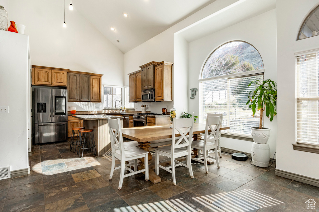 Dining room featuring high vaulted ceiling, stone tile floors, baseboards, and recessed lighting