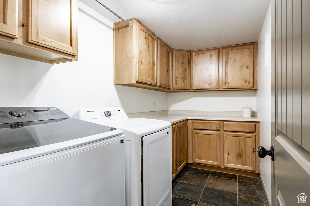 Washroom with washing machine and dryer, stone finish flooring, and cabinet space