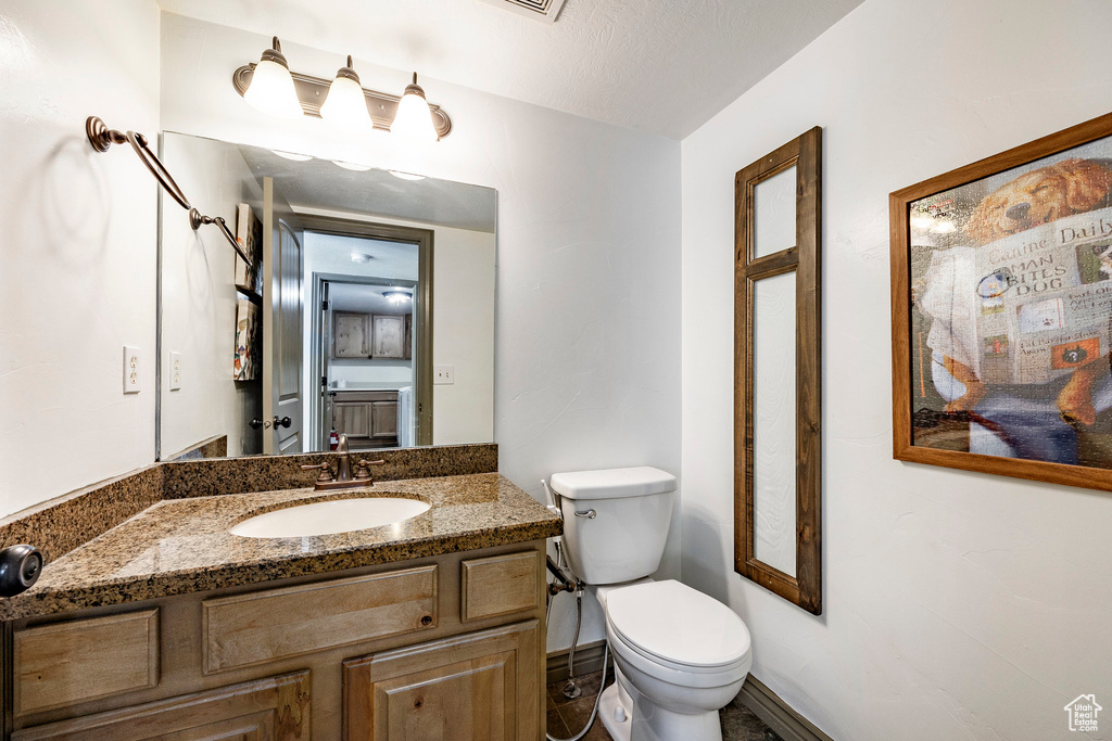 Half bathroom featuring toilet, vanity, and baseboards
