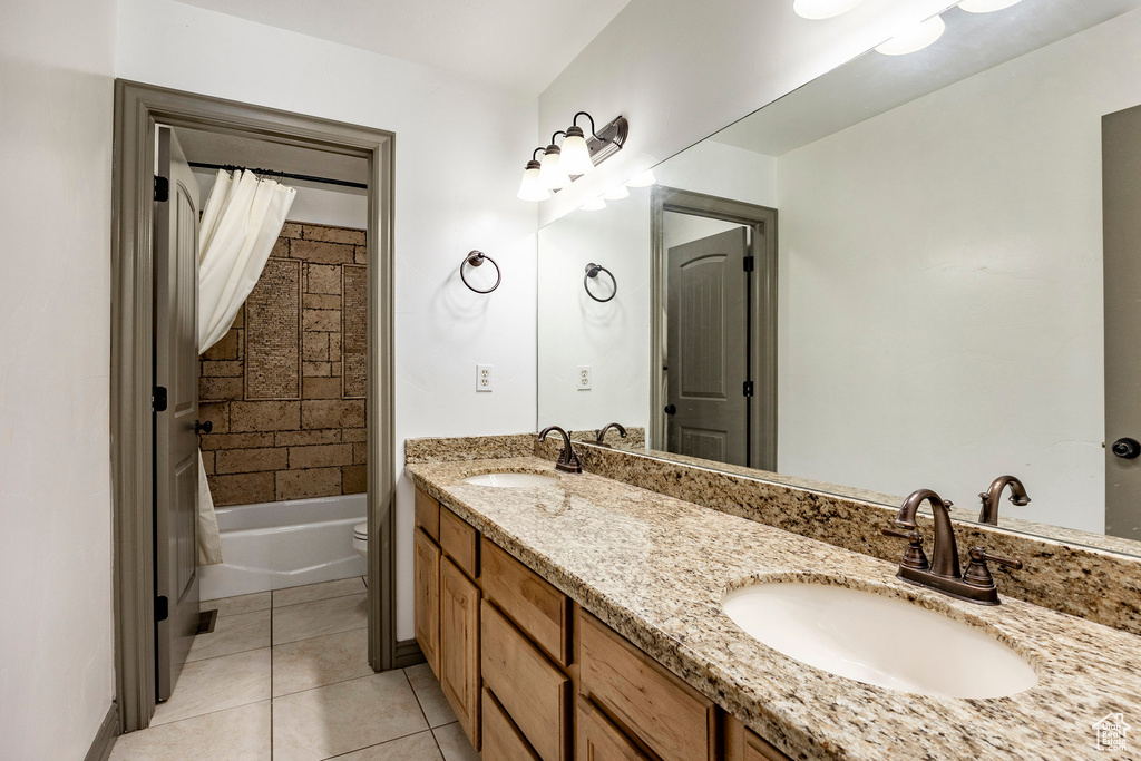 Bathroom with tile patterned floors, double vanity, toilet, and shower / tub combo with curtain