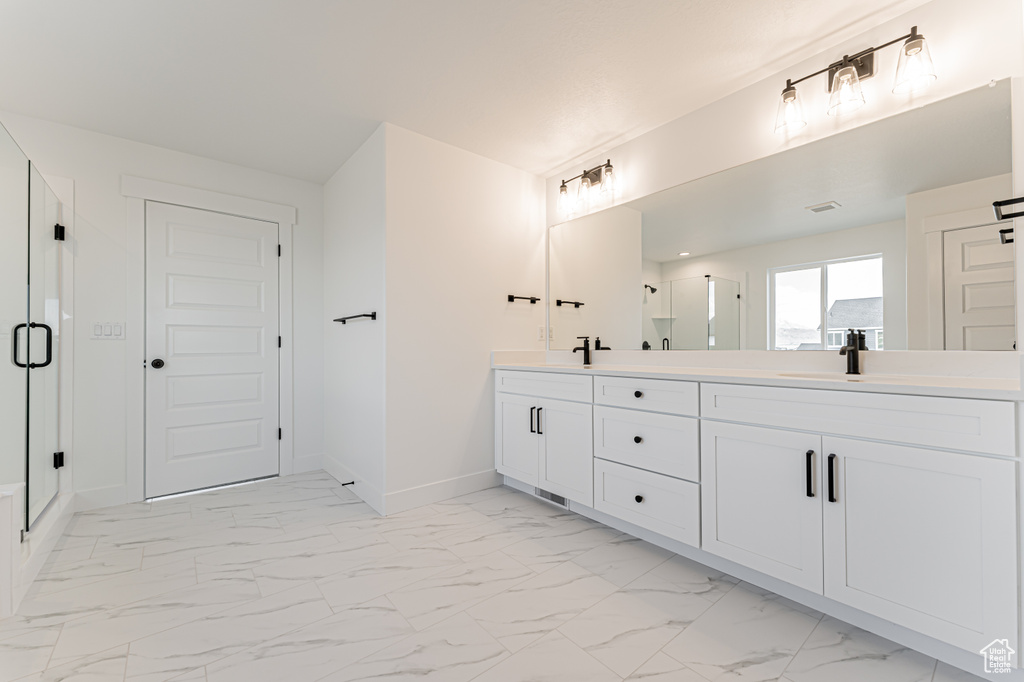 Full bath featuring double vanity, a shower stall, and marble finish floors