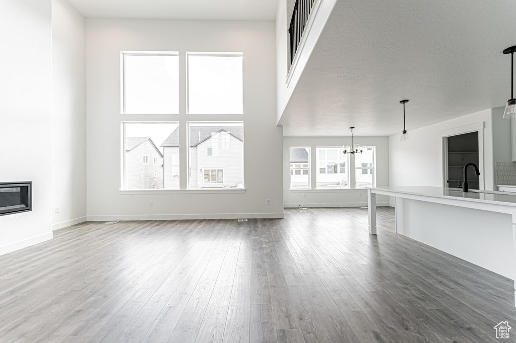 Unfurnished living room with a chandelier, wood finished floors, and a glass covered fireplace