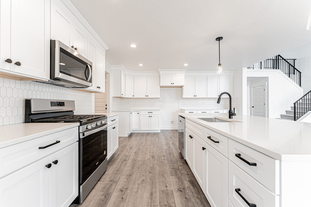 Kitchen featuring stainless steel appliances, decorative backsplash, white cabinetry, light wood finished floors, and recessed lighting