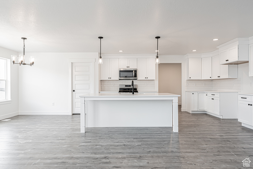 Kitchen featuring stainless steel appliances, decorative backsplash, a chandelier, recessed lighting, and light wood-style flooring