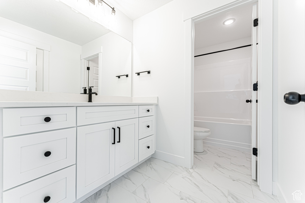 Bathroom featuring vanity, marble finish flooring, washtub / shower combination, and recessed lighting
