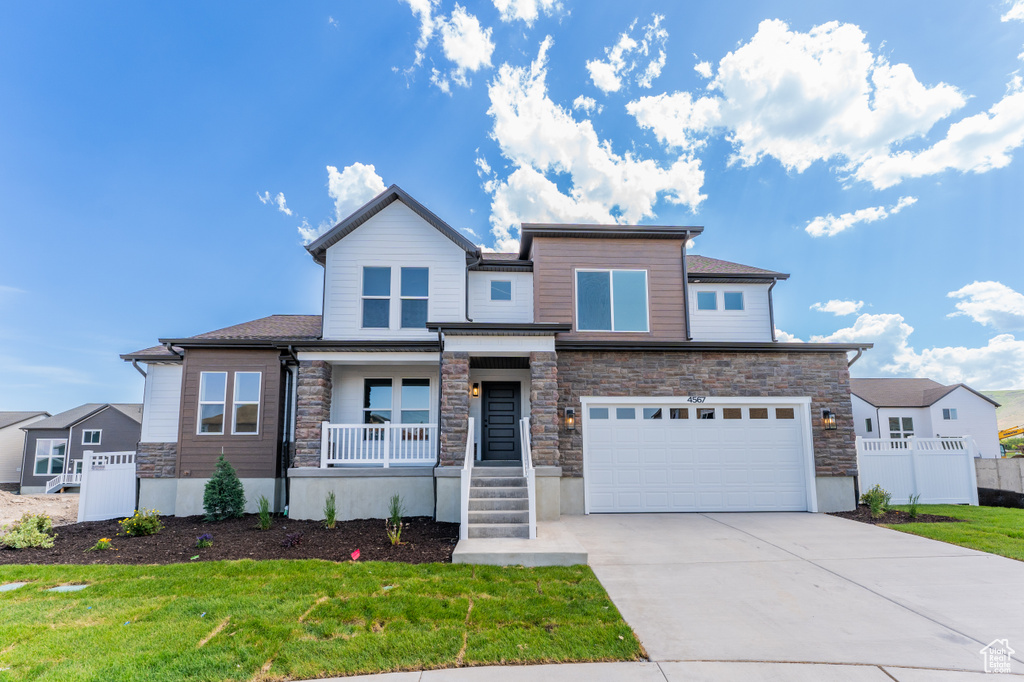 View of front of house with covered porch, an attached garage, stone siding, and concrete driveway
