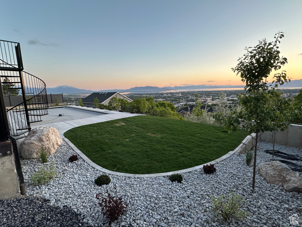Yard at dusk featuring stairs, a yard, and a mountain view