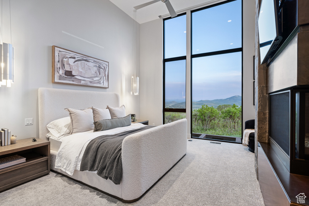 Carpeted bedroom with floor to ceiling windows, a towering ceiling, and a mountain view
