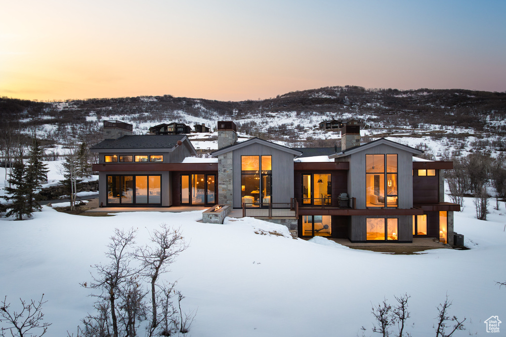 Snow covered property featuring a chimney and stone siding