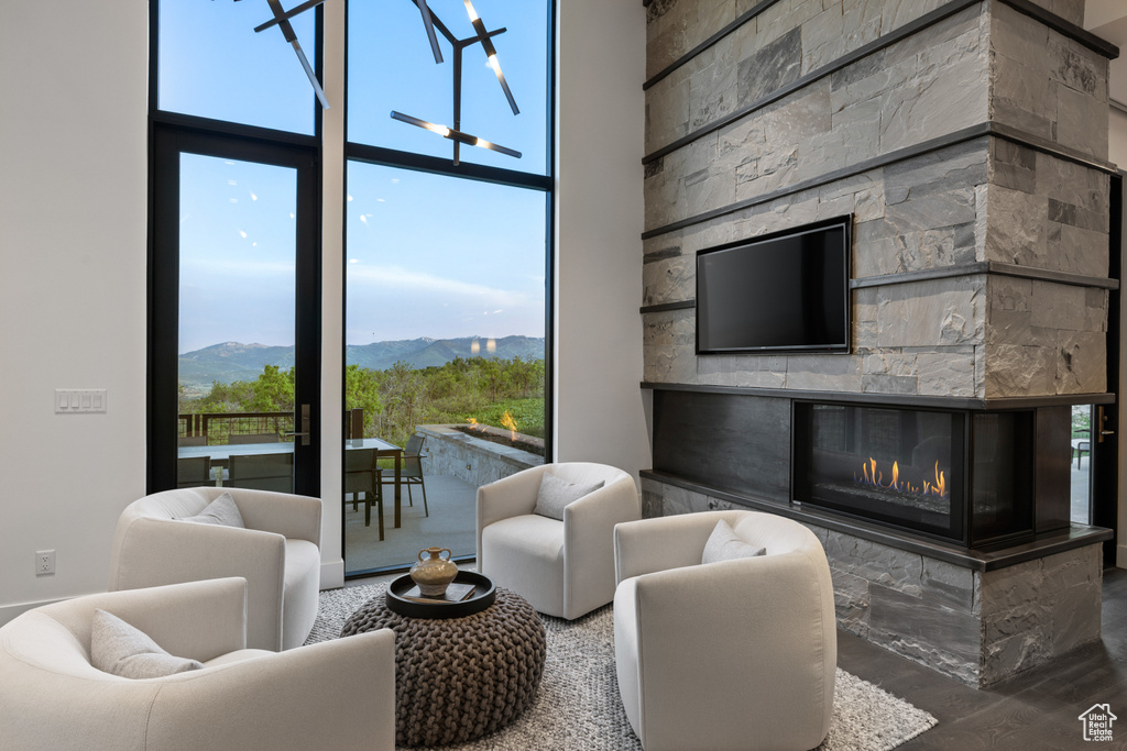 Living area with a fireplace, a high ceiling, and a wall of windows