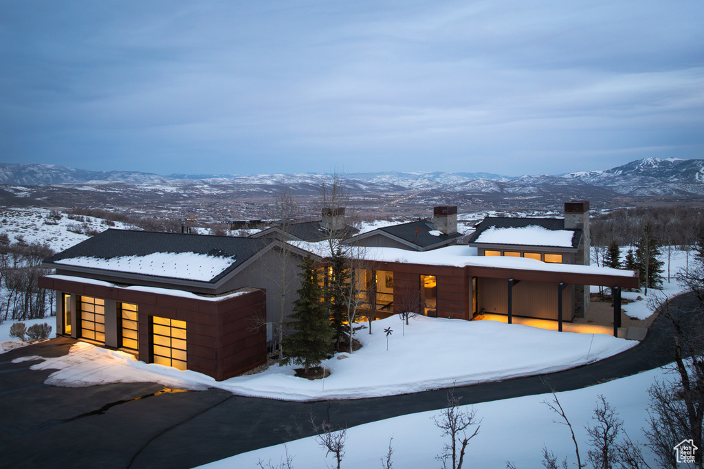 Snow covered rear of property featuring a chimney and a mountain view